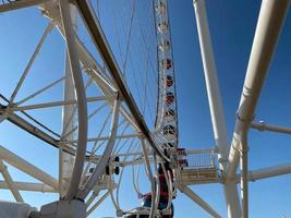 Big white ferris wheel against the blue sky. Part of the attraction on a blue background with copy space. Cabins, viewing photo