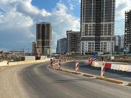 reparación y construcción de una carretera con señales de carretera temporales y conos en el fondo de hermosos edificios nuevos y altos en el fondo del cielo azul y el arco iris en una gran ciudad foto