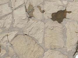 Texture of old stones of various forms with seams. Close up of shabby masonry. Stone wall from uneven different ancient friable cobblestones photo