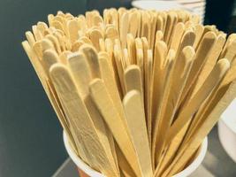 wooden sticks for stirring the drink. many sticks in a plastic glass. coffee machine at a gas station. preparation of hot drinks. stirring sugar and bulk coffee additives photo