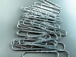 Shiny metal paper clips on a desktop with stationery in a business office. Close view photo