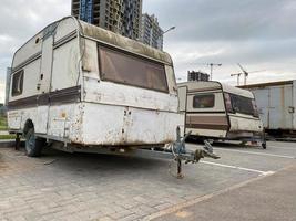 Old white rusty caravan trailers, mobile homes are parked photo