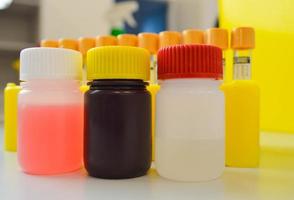 reagents for performing laboratory tests. liquid media in multi-colored containers for laboratory diagnostics. against the background of a test tube in a holder photo