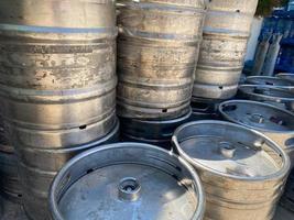 Group of aluminum beer kegs. Refrigerated beer kegs ready for distribution. Stacked in a row large silver or metallic colour alcohol barrels or containers photo