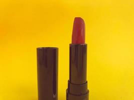 lápiz labial en un paquete compacto negro sobre un fondo amarillo mate. lápiz labial rojo brillante, creación de sombra, hidratación de labios. sombra elegante y de moda foto