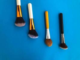 four brushes with natural bristles on a blue background. brushes for applying foundation, powder, blush, contouring. creating the perfect face. makeup artist tool photo