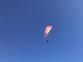 Skydiver is flying with parachute in blue sky photo