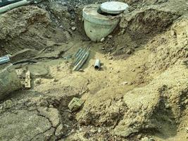 las comunicaciones para el drenaje del agua se colocan en el suelo. un gran pozo hecho de anillos de hormigón con tuberías. colocación de tuberías de plomería para casas nuevas foto