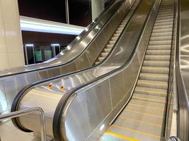 Large comfortable fast metal modern escalators with automatic steps for going up and down the subway or shopping and entertainment center photo