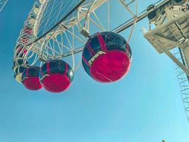 Ferris wheel in the city center against the blue sky. red booths rise in a row, rolling tourists. sightseeing tour on the carousel. ride on the attraction photo