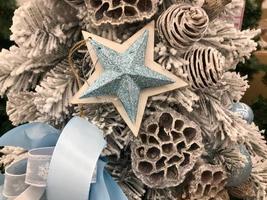 Christmas star on a fir branches on festive golden lights background, night illumination. New Year tree with decorations, magic of a holiday for background photo