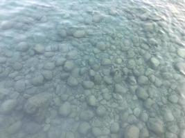 Sea stones in the sea water. Pebbles under water. The view from the top. Nautical background. Clean sea water. Transparent sea photo