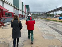 a man and a woman are walking at an industrial plant, the view from the back photo