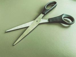 stationery on the table in the office. metal scissors with black handles. paper cutting, tool for work. cropping documents for attachment to folders photo