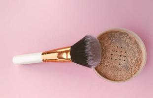 powder brush on a bright pink background. face powder and brush. loose matte powder to match the skin. mineral powder for make-up and tone creation photo