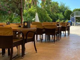 Beautiful view of outdoor tables. Blue chairs and orange umbrellas on green palm trees and blue sky background. Key West, Florida. USA photo