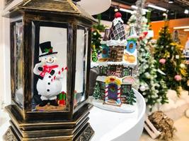 mini muñeca blanca de hombre de nieve en el árbol verde, decoración navideña durante la temporada festiva de año nuevo foto