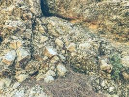 high mountains in a hot, tropical country. texture with sand and stones. mountain with green bushes and herbs. plant roots and dry grass on the stones photo