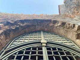 Large iron metal gate, passageway, doorway, archway in an old ancient medieval fortress made of cobblestones and bricks in a tourist warm tropical eastern country photo