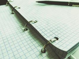 a sheet of white paper in a cage from a notebook. diary to record all personal affairs and tasks. retro notepad with black ballpoint pen for writing thoughts photo