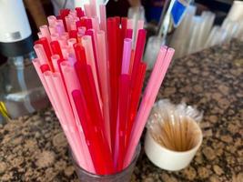 Pink plastic drinking straws in blue disposable paper cup. Cafe, fun happy vacation, summer cocktail party, poster banner design, men women boy girl concept. Copy space photo