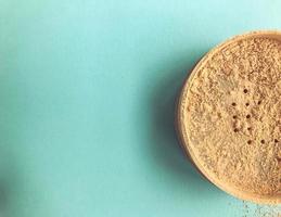 loose powder on a blue background. round shape of the jar. mineral, useful powder with glitter particles. face makeup, oily skin toning photo