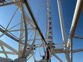 Big white ferris wheel against the blue sky. Part of the attraction on a blue background with copy space. Cabins, viewing photo