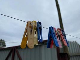 Colorful clothespins on a clothesline against the sky and grass photo