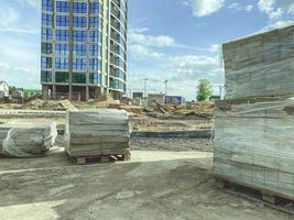 construction of a new residential area in the city. construction of high, multi-storey buildings from building materials. on the site there are blocks under the film photo