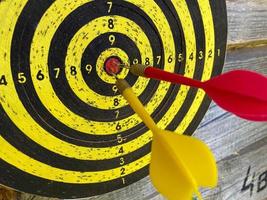 Large playable yellow and black dartboard or darts in the bar against the background of a wooden wall photo