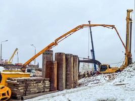 construction of a bridge in the city center in winter under snow. machines for the erection of large concrete structures. heavy concrete blocks for the bridge photo