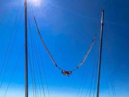 catapult on top of the mountain. attraction for adults, a huge trampoline against the blue sky. orange fabric seat for jumping people photo