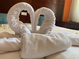 White two towel swans on the bed photo