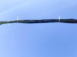 Thick black electrical industrial high voltage wire cable on a blue sky background photo