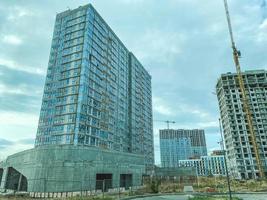 construction of multi-storey buildings in the city center. tall houses made of concrete blocks and slabs. modern high-rise buildings made of glass, with panoramic windows photo