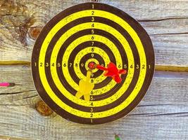 active outdoor games. darts with darts on a rustic log background. shooting a dart with a feather straight at the target. yellow field with marks points. game of accuracy photo