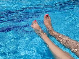 hermosas piernas de mujer chapoteando en la piscina foto