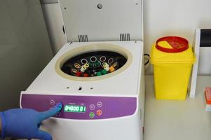 tubes are placed in the analyzer for centrifugation. performing laboratory tests. the doctor puts the test tube and selects the mode on the device. venous blood tests photo