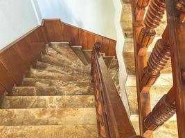 escaleras empinadas en el hotel. pasamanos de madera, escalones de mármol para el descenso de turistas al vestíbulo. escalera de azulejos. pasamanos y paredes de madera marrón foto