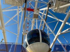 Low Angle View Of Ferris Wheel Against Blue Sky During Sunny Day photo