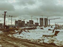 construcción de casas, un centro comercial de bloques de hormigón en la ciudad. construcción de un nuevo barrio residencial en invierno. el equipo está trabajando en el sitio, rastros de neumáticos grandes foto