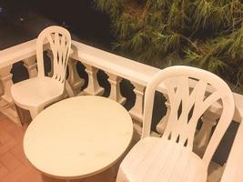 sillas de plástico en el balcón del hotel. muebles de exterior, recreación al aire libre. mesa y dos sillas para descanso. muebles cercados, juego de muebles baratos foto