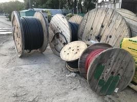 large, wooden, beige spools with coiled black cable. creation of communications in the city center for a new microdistrict under construction photo