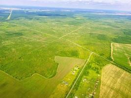 viajar por el cielo a otro país. el avión se eleva en el cielo. vista de los campos verdes y limpios desde una altura. cerca de los mares y océanos de color azul foto