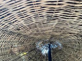 Low angle view of a wicker umbrella on the beach. Close up of a wicker beach umbrella on a sunny day, sky in background photo