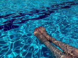 mujer agradable sosteniendo sus piernas en la piscina. foto