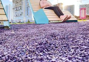 purple color stones, texture. filling of stones, decorative elements on stones, wooden seats. a girl in pink shoes is sitting on the seat. background with stones, small rocks photo