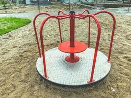 carousel for children to ride on the playground. outdoor games. red carousel made of metal with a wooden base for a fun time for children photo