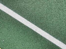 Green rubber surface of a tennis court anti-traumatic safety tile on a workout sports playground in a public park or courtyard. The background. Texture photo