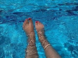 Woman's legs over the swimming pool photo